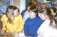 photo of little girls painting each others' faces at a birthday party. Eleanor is in the center.