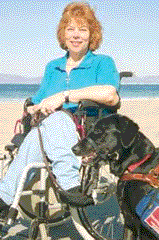 photo of Daniese with her dog at what looks like a beach. Daniese uses a wheelchair.